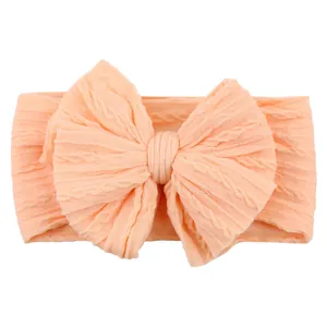 Elastic baby headband with large jacquard bow in soft apricot color for infants