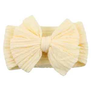 Pale yellow elastic baby headband featuring a large knitted bow and cable pattern