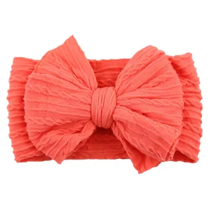 Elastic coral red baby headband with a large textured jacquard knit bow decoration