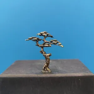Detailed view of miniature bronze pine tree craft with textured needles and metal base