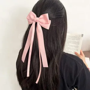 Elegant light pink satin bow hair clip with long ribbons on dark hair