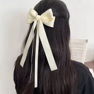Elegant cream white satin bow hair clip with long ribbons shown on hair