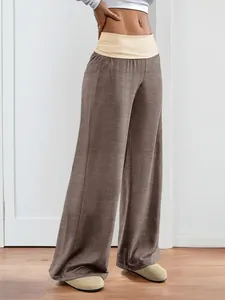 Detail of the high-waisted wide-leg trousers featuring a beige contrast waistband design