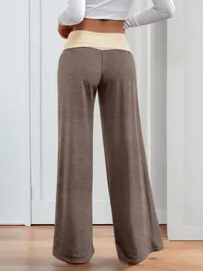 Detail view of contrast patchwork waistband on brown wide leg trousers for women