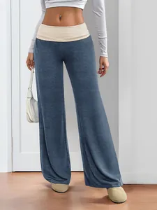 Detail of wide-leg trousers featuring a color-contrast waistband and fluid drape