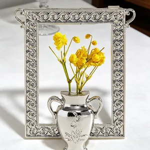 Detailed view of silver embossed flower vase with yellow dried flowers and frame