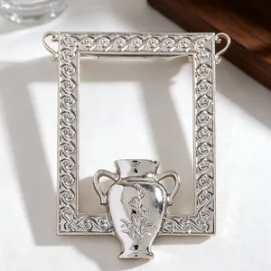 Macro shot of silver retro flower vase brooch with embossed patterns and polished finish