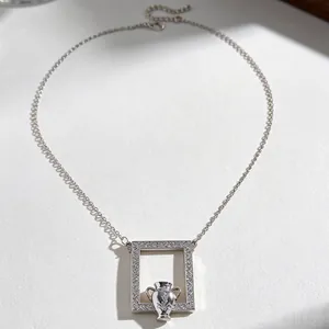 Detailed macro of a silver picture frame pendant with a miniature vase on an O-chain