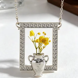 Macro shot of silver rectangle frame pendant with yellow flowers and ornate details