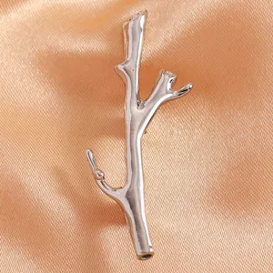Close-up of artistic silver bionic branch brooch on elegant champagne satin fabric