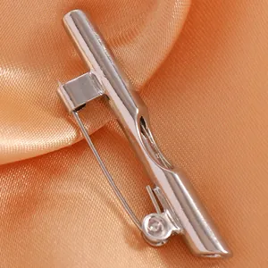 Macro close-up of silver metal brooch pin with secure rotating safety clasp on orange satin