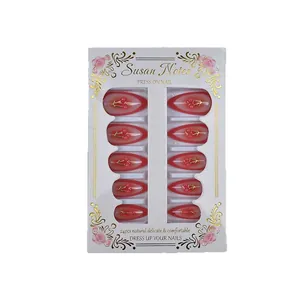 Red cherry press-on nails with golden branches on almond shaped artificial nail tips