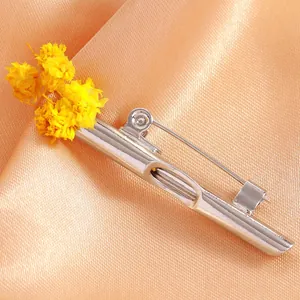 Detailed view of silver flower tube brooch with dried yellow flower on satin background