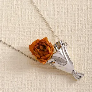 Macro shot of silver bouquet pendant with dried orange rose and minimalist chain