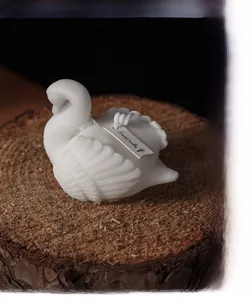 Detailed view of a white swan-shaped scented candle with intricate feather texture on wood