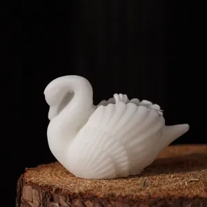 Elegant white swan scented candle with detailed feather carving on a rustic wood base