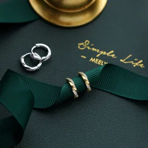 Close-up of twisted gold and silver hoop earrings with zircon pavé on a gift box