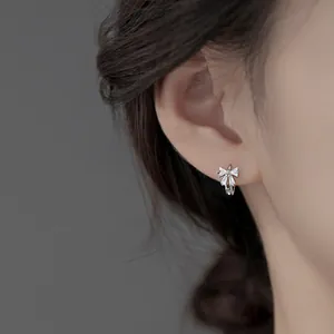 Detail of silver bow earrings with sparkling cubic zirconia on a female model