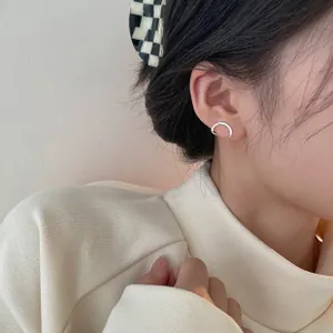 Minimalist U-shaped silver zircon hoop earrings shown on model for a modern aesthetic