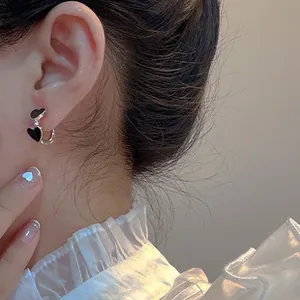 Close-up of elegant black heart-shaped zircon earrings worn by a model in soft lighting