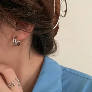 Detail of silver S925 earrings and open ring set worn by model in a stylish shot