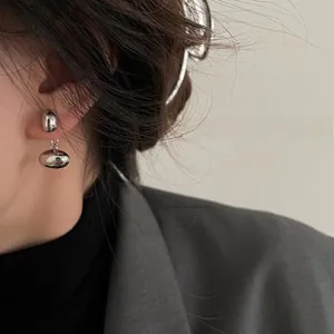 Close-up of minimalist silver drop earrings with geometric stone on female model