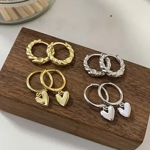 Detail shot of twist texture hoops and heart pendant earrings set in gold and silver