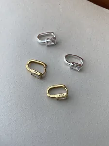 Detail of S925 sterling silver stamp on minimalist gold and silver earrings with zircon