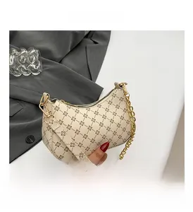 Detail of cream shoulder bag with dark geometric floral prints and gold chain strap