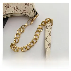 Detail of vintage patterned cream PU leather bag with gold metal chain and floral strap