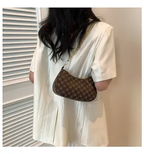Detailed view of a dark brown crescent underarm bag with gold chain on a model