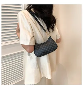 Detail of printed crescent shoulder bag with golden hardware on a white silk shirt