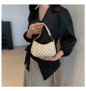 Close-up of golden chain strap and geometric print texture on beige crescent bag