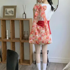 Floral shoulder tote bag with oversized bow strap detail on a female model