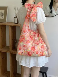 Floral print hobo shoulder bag with a large decorative bow and drawstring closure