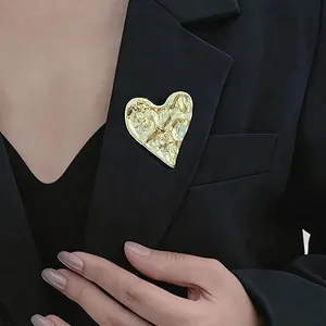 Detailed view of irregular hammered gold heart brooch on a black blazer lapel