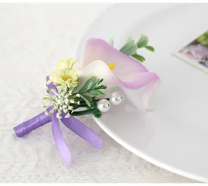 Macro shot of calla lily wedding corsage with purple ribbon and pearl details