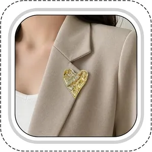 Detail of a textured golden heart brooch pinned on a beige blazer collar for women