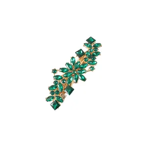 Vue détaillée de strass vert émeraude sertis sur une pince à cheveux dorée vintage