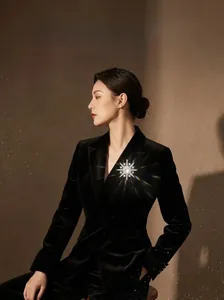 Detailed view of a 4.2cm silver starburst brooch with crystals on a black suit