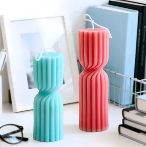Detail view of blue and coral ribbed spiral pillar candles on a modern white desk