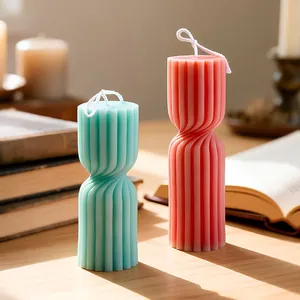 Modern spiral ribbed pillar candles in mint green and coral pink on a wooden desk