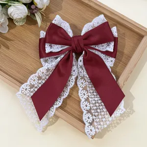 Detail of burgundy satin and white lace double-layered bow hair clip on a wooden tray