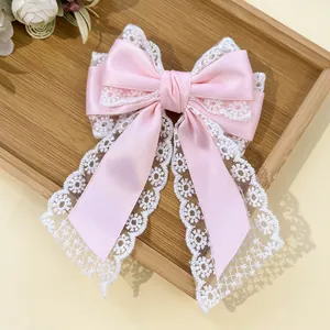 Detail of pink satin bow hair clip with elegant white lace trim and delicate textures