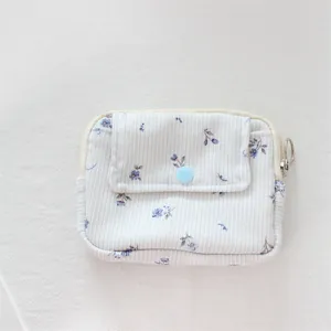 Detail view of the floral corduroy pouch with a button pocket and silver zipper ring