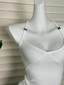 Dettaglio di canotta bianca in maglia con taglio a V incrociato e fibbie in metallo argento