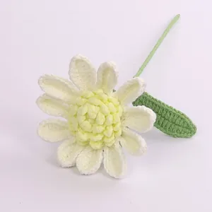 Handmade crochet white daisy flower with yellow center and green stem on lilac backdrop