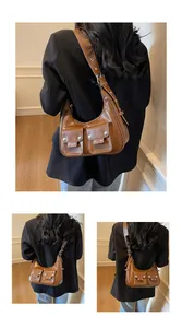 Detail of retro brown crescent leather shoulder bag with pockets and metal buckles