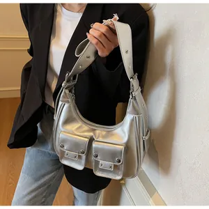 Close-up of silver crescent bag with metal studs and twin front pockets in Y2K style