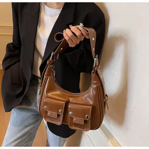 Detail of a brown retro hobo bag featuring two flap pockets and silver metal rivets